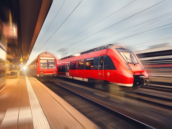 modern high speed red passenger trains at sunset leaving railway station